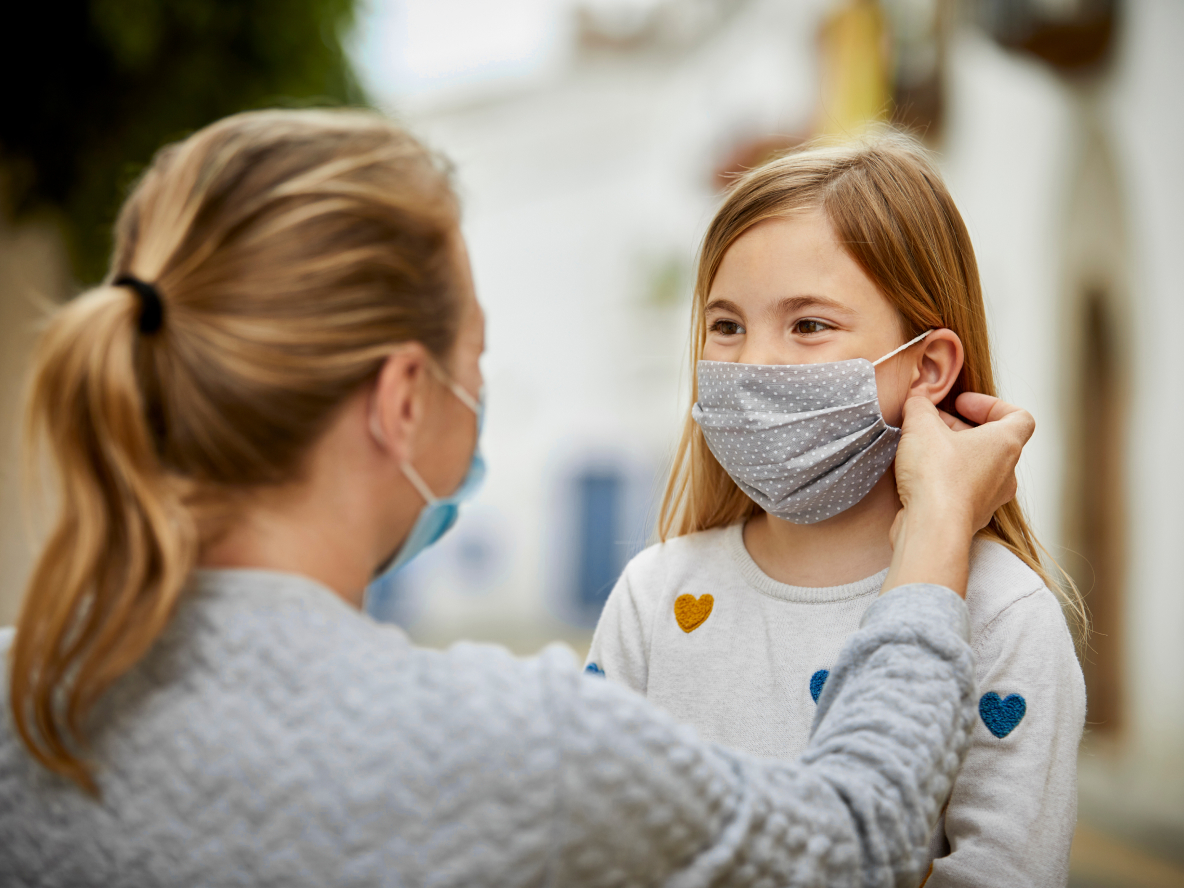 Woman helping child with mask