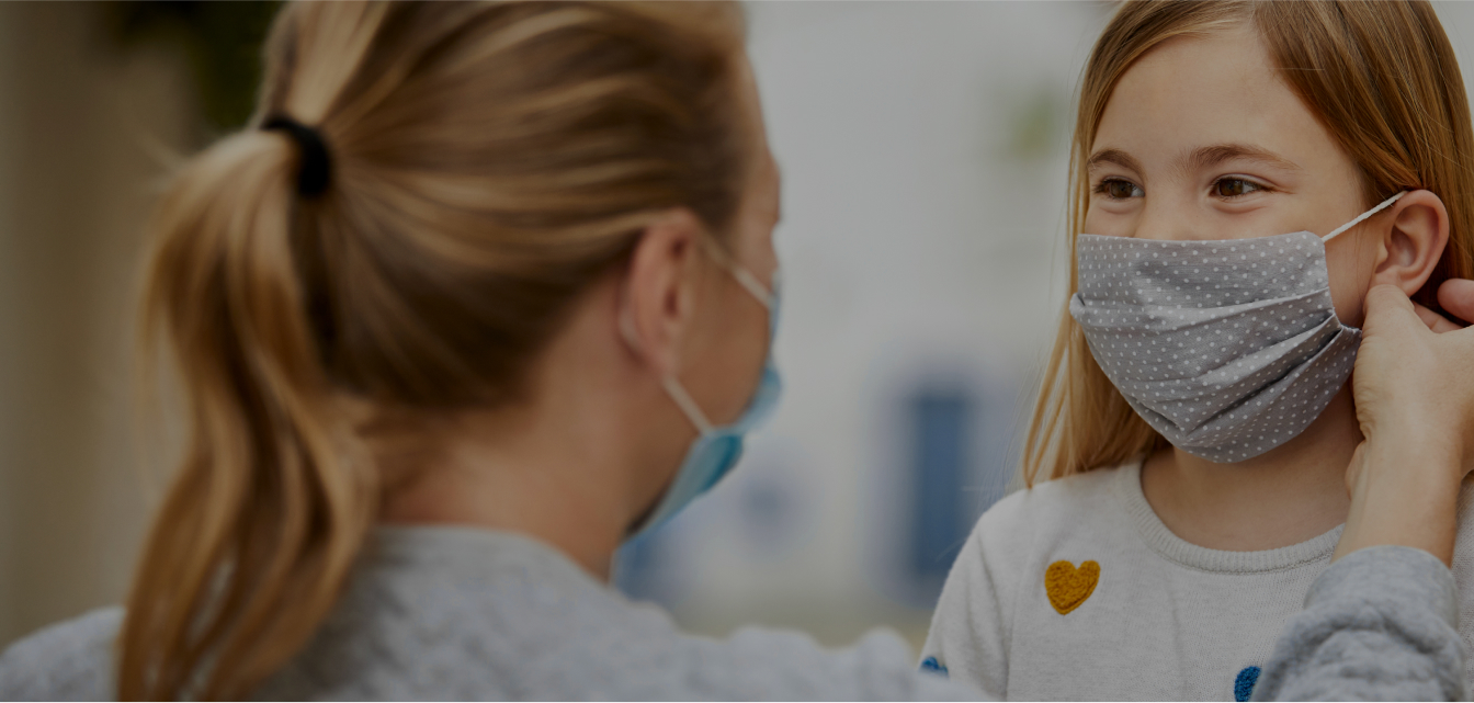 Woman helping child with mask